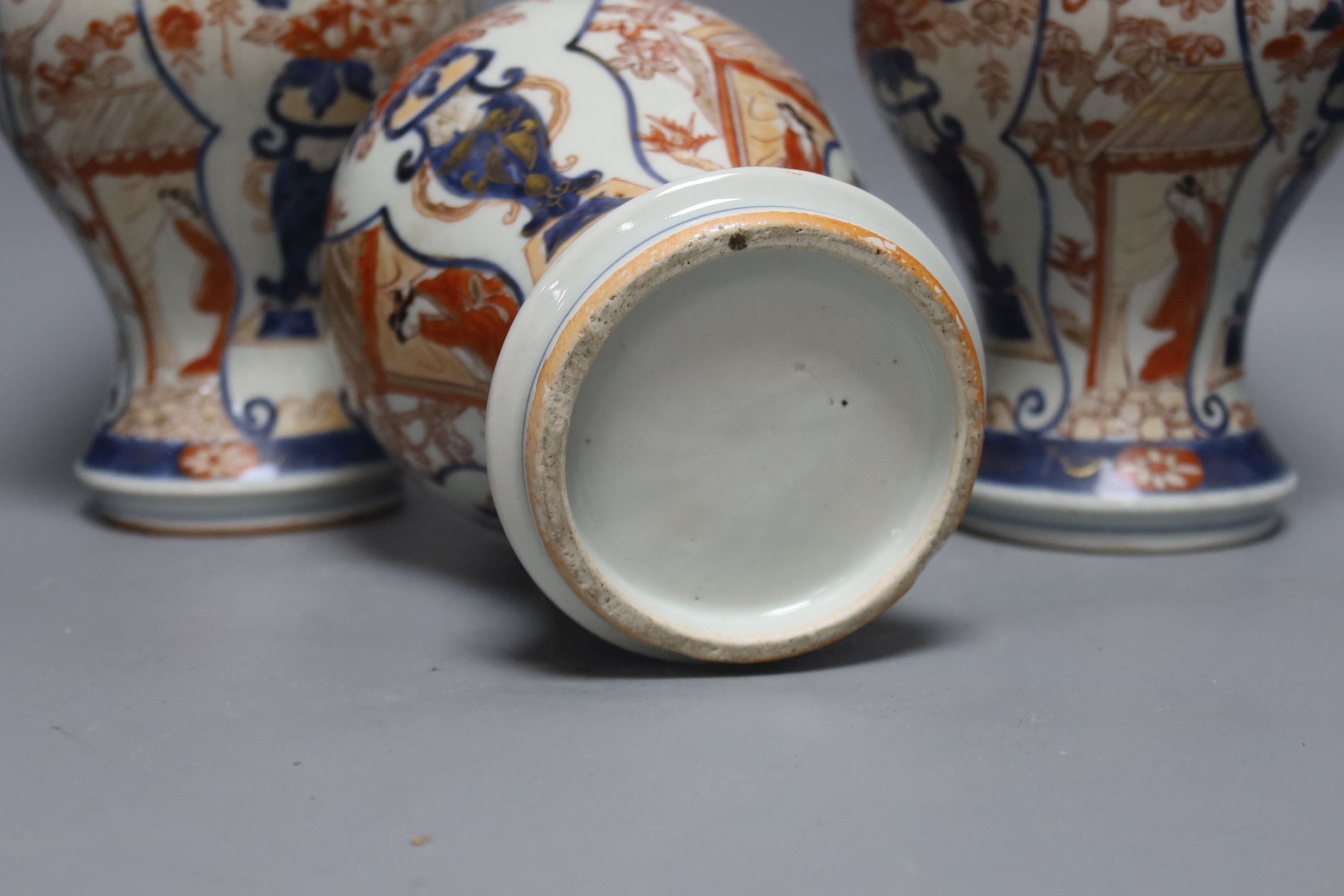 Three 18th century Japanese Arita baluster vases and covers decorated with flowers in urns (damage to covers) 29cm